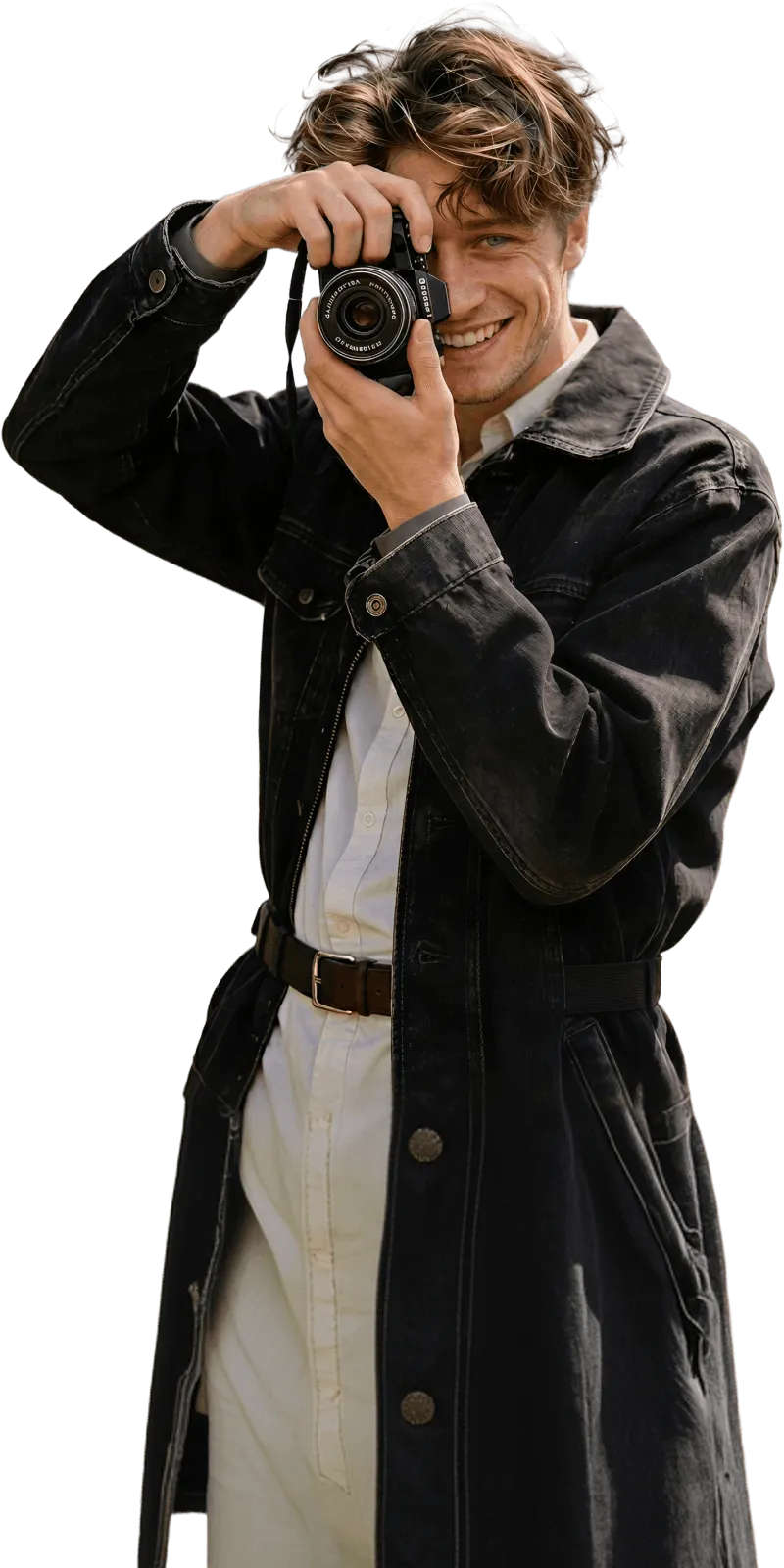Photographer Elian Moreau aiming a camera upward while smiling, wearing a dark trench coat
