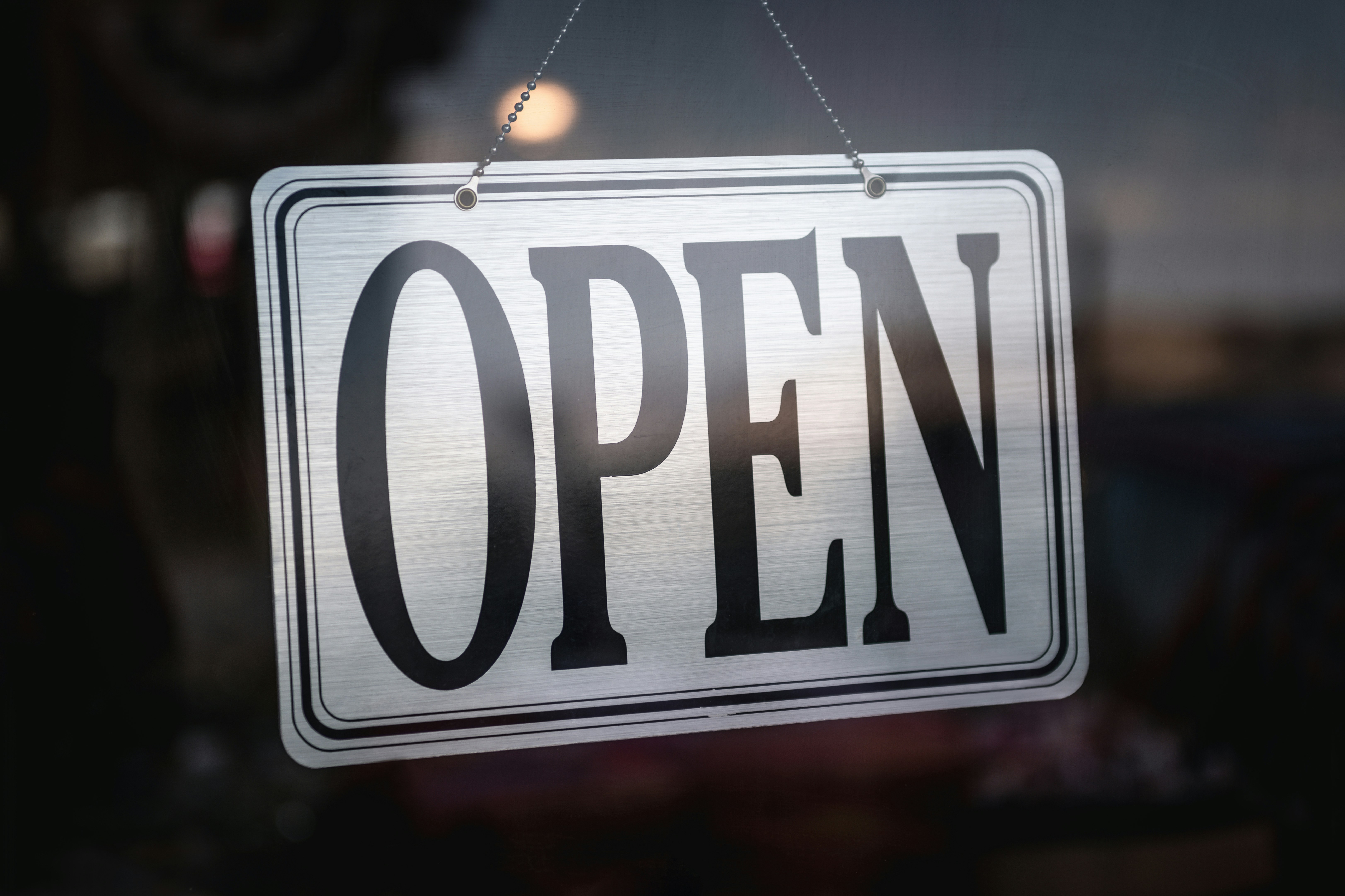 an open sign hanging from a glass door