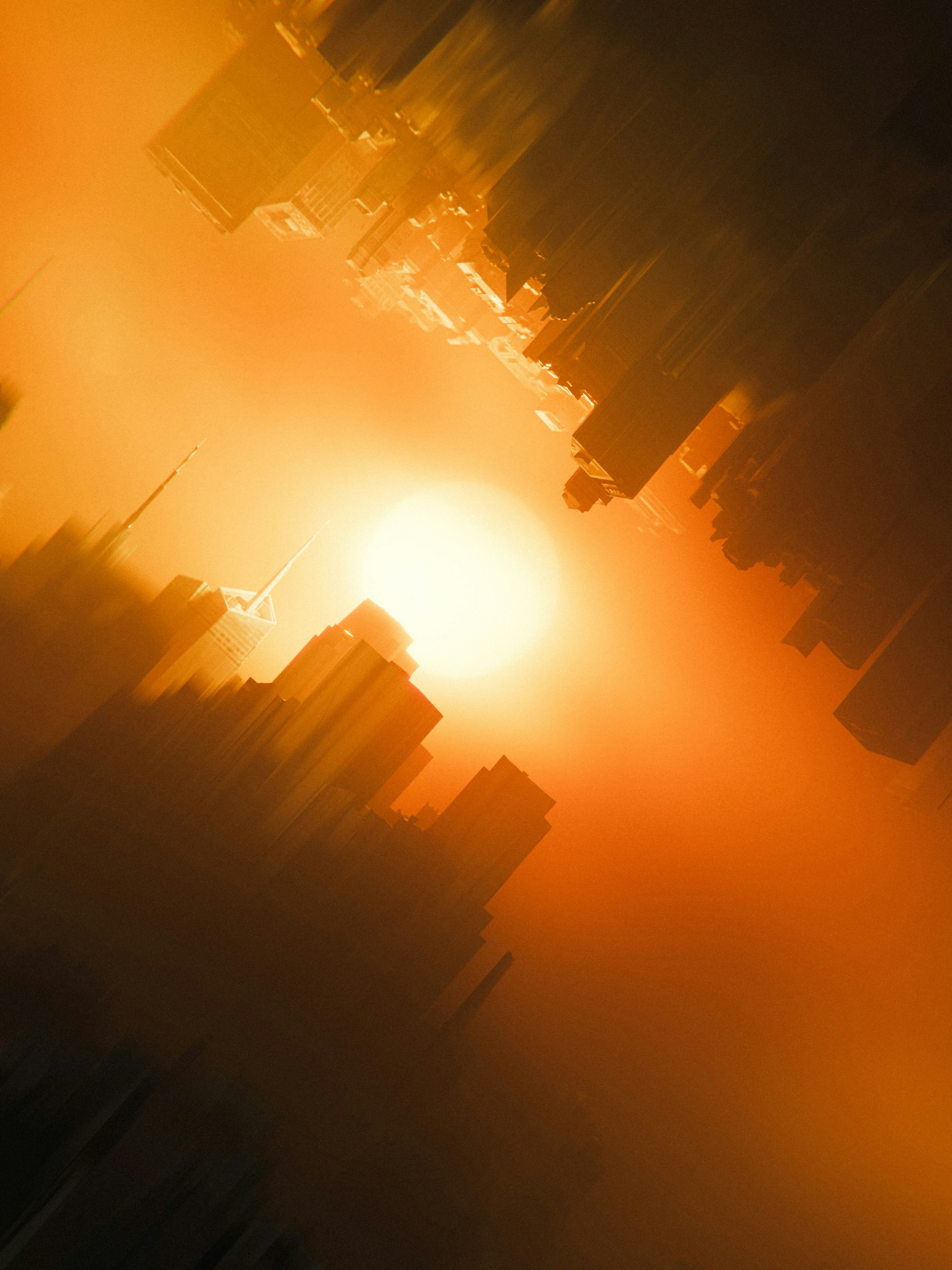 Abstract cityscape with mirrored skyscrapers against a glowing orange sun.