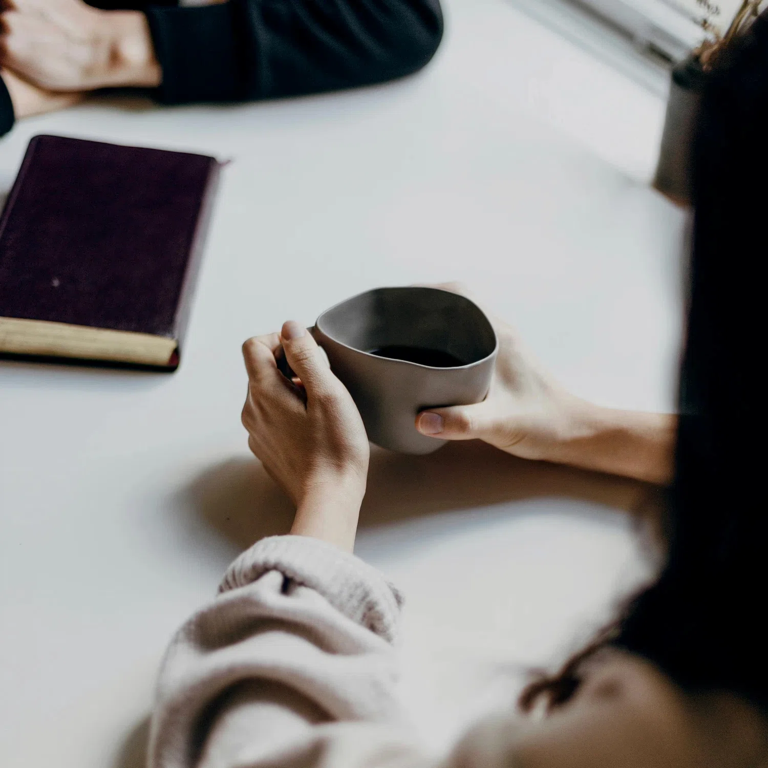 Close-up of a person holding a cup of coffee during online therapy session