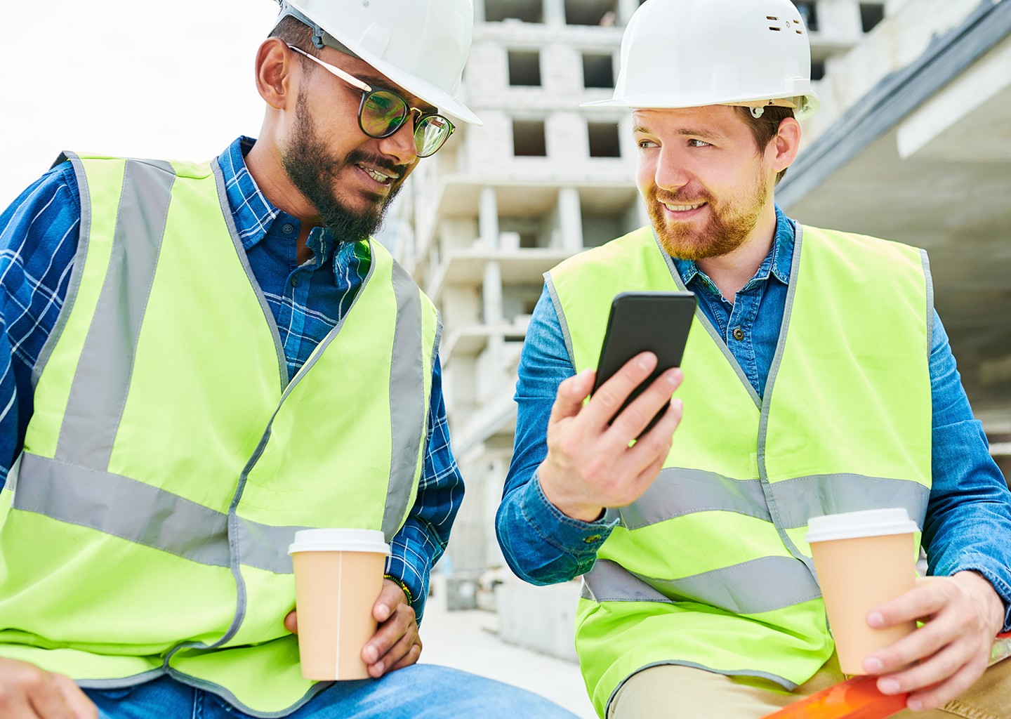 Alcuni operai in un cantiere all’aperto stanno discutendo confrontando gli schermi dei loro smartphone, dove è aperta l’app Fluida