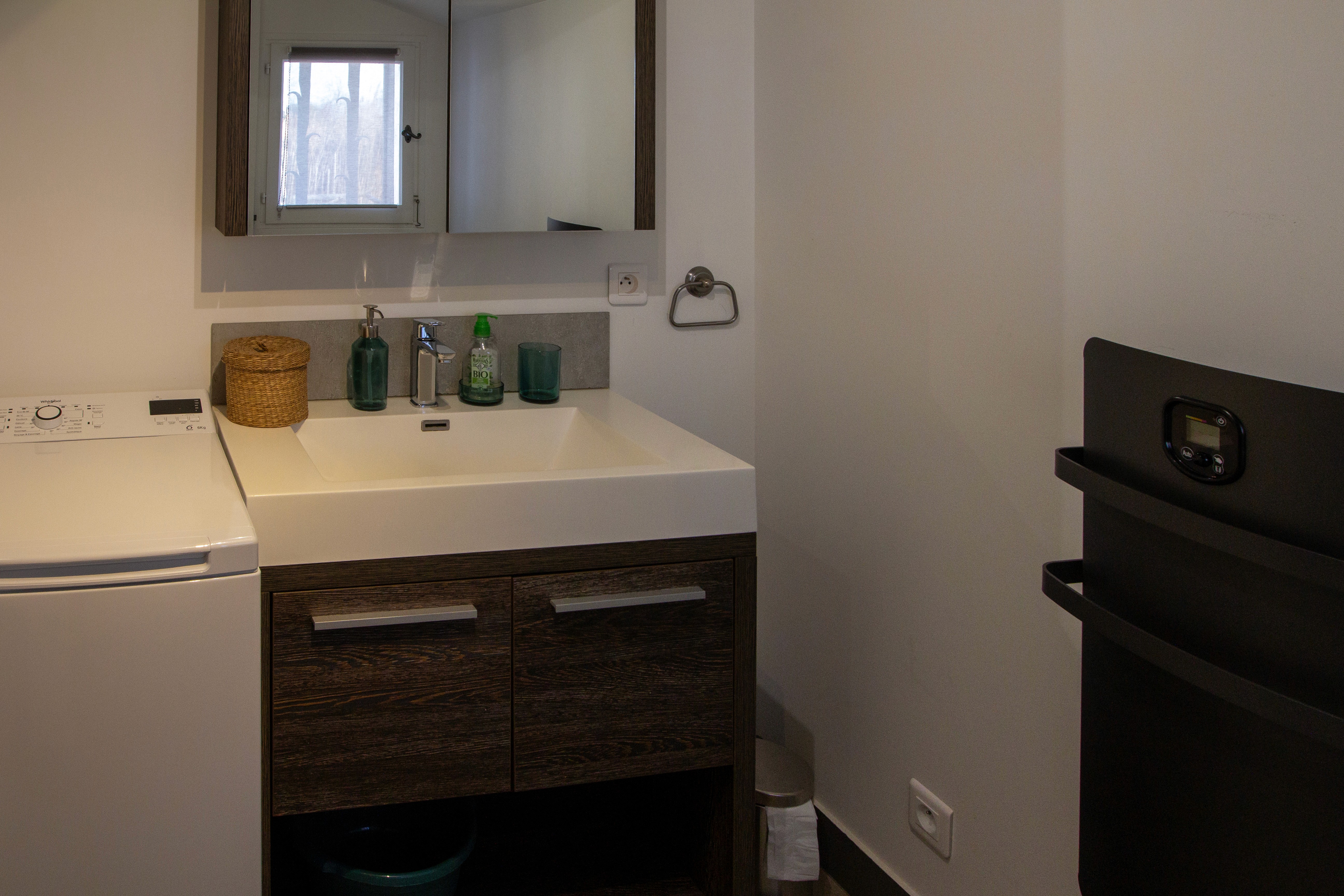 Aménagement salle de bain zen avec douche à l'italienne en travertin, meuble en bois clair et décoration bohème.