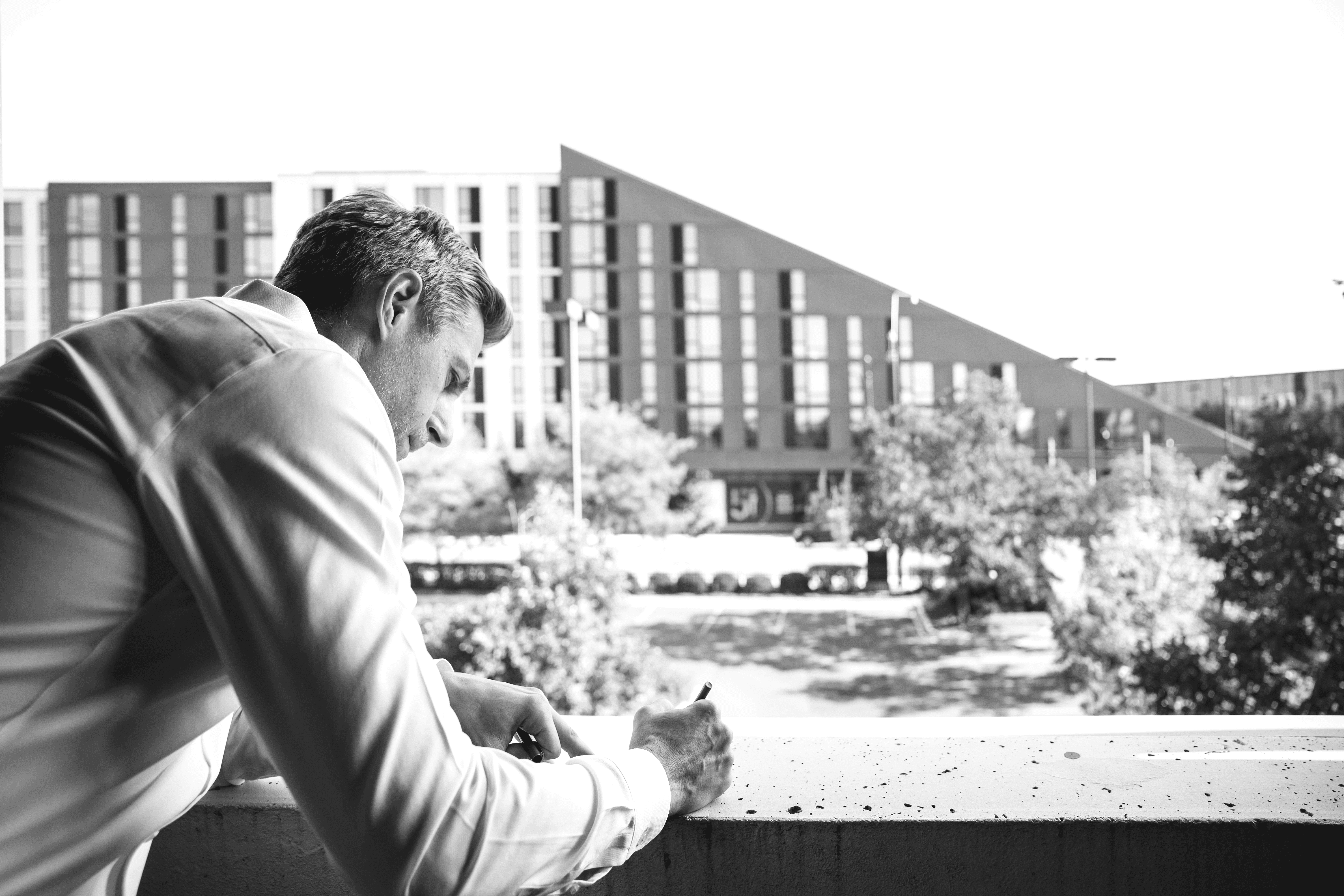 Modern red brick apartment or office building viewed from below against a blue sky, showcasing its geometric architecture with evenly spaced windows and balconies.