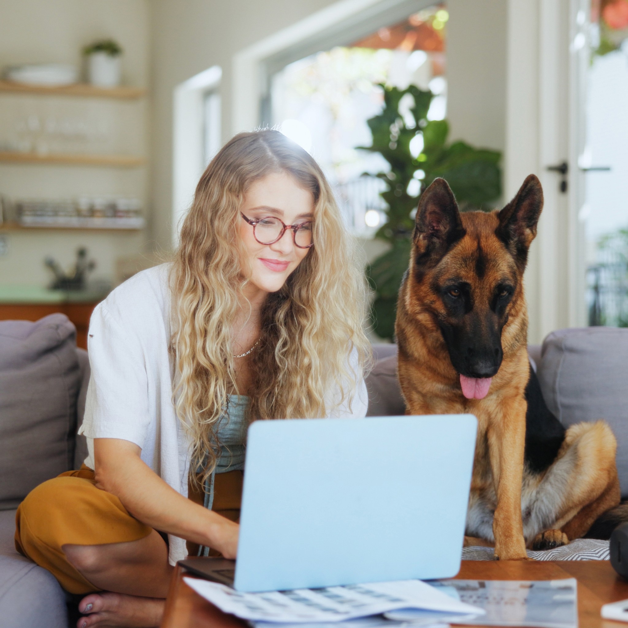 Naine vaatab sülearvutit, kõrval istub koer.