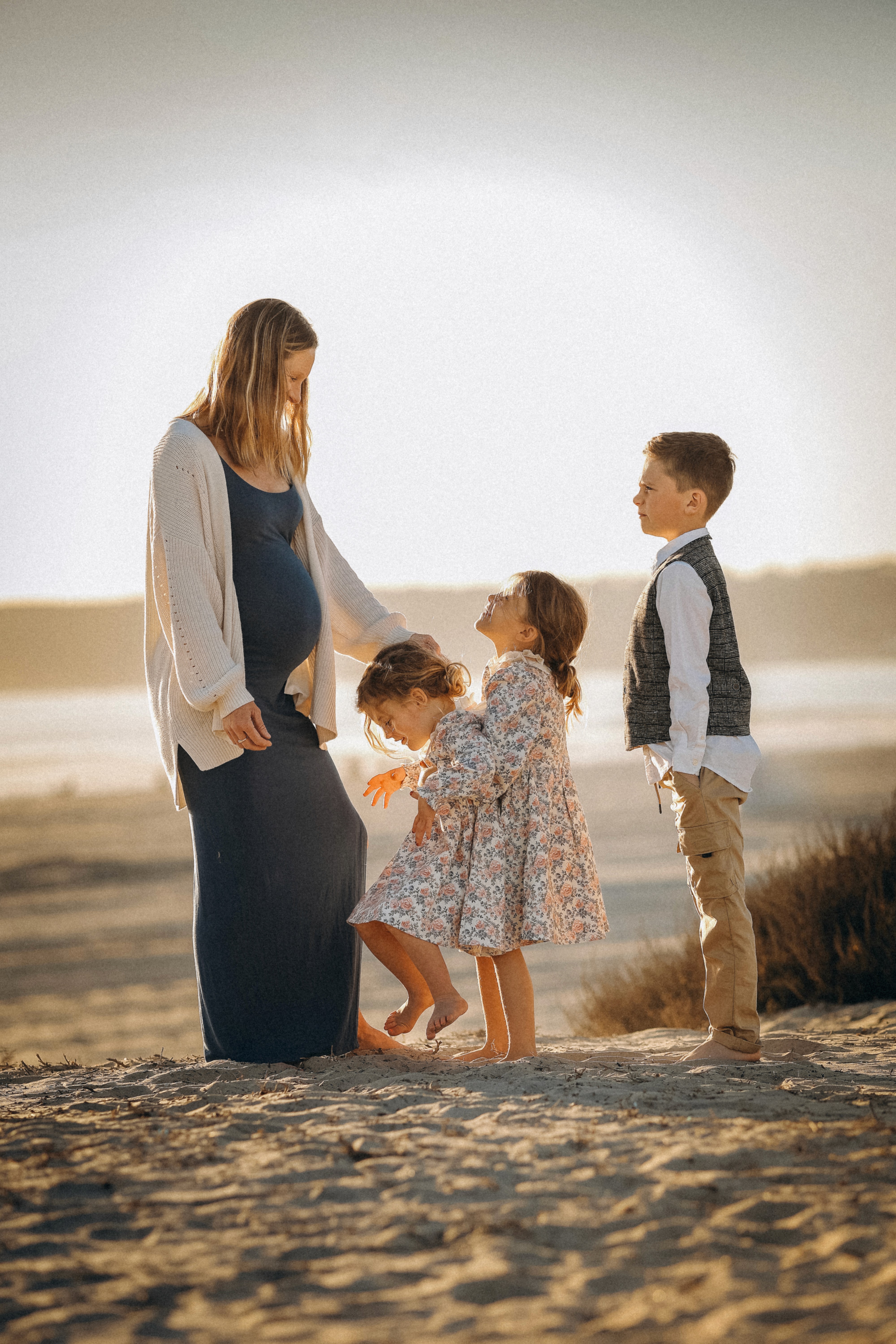 Mother and children walking along the coastline during golden hour.