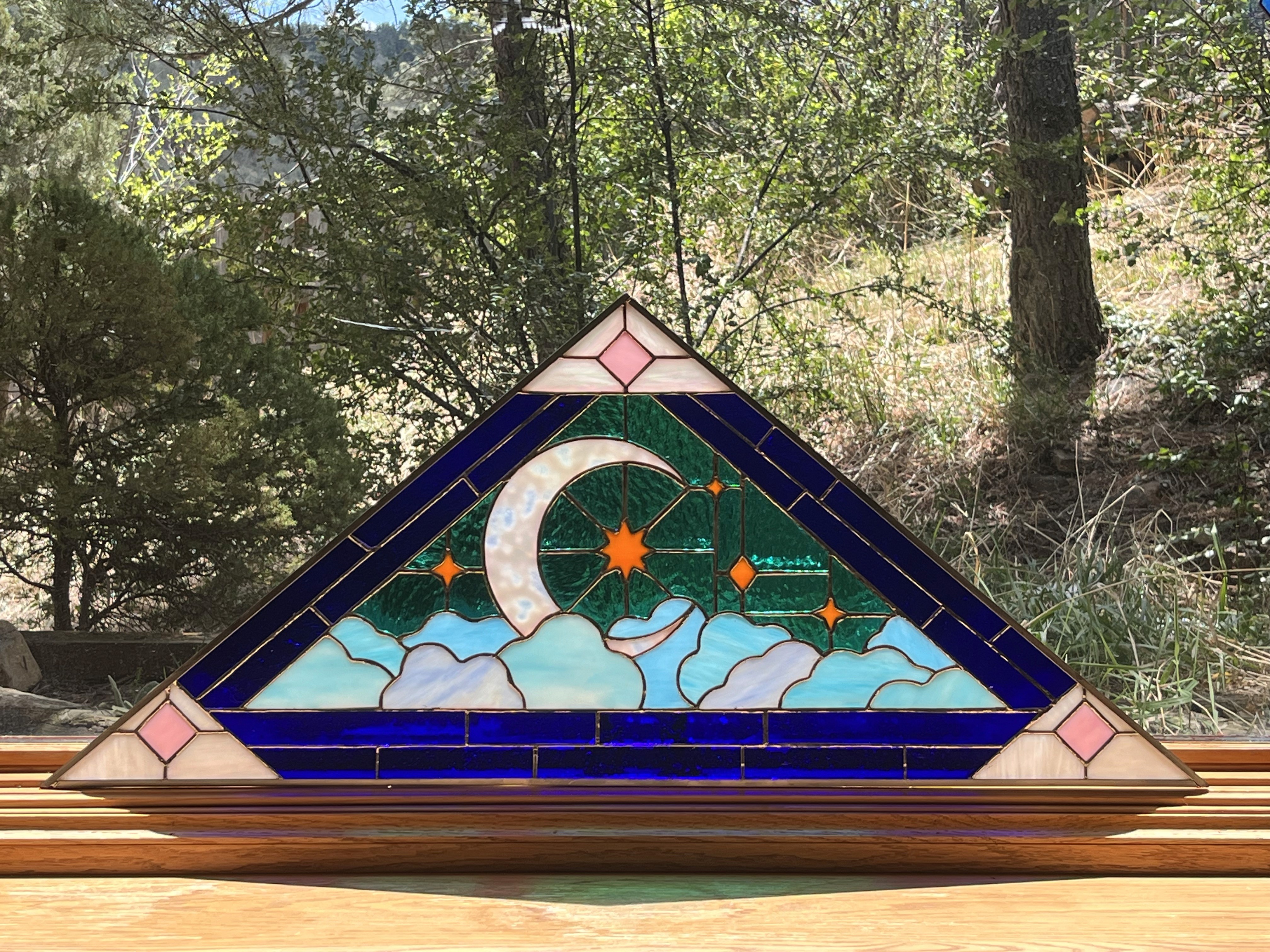 Mountain-inspired stained-glass panel with a moon and star details held outdoors in Colorado