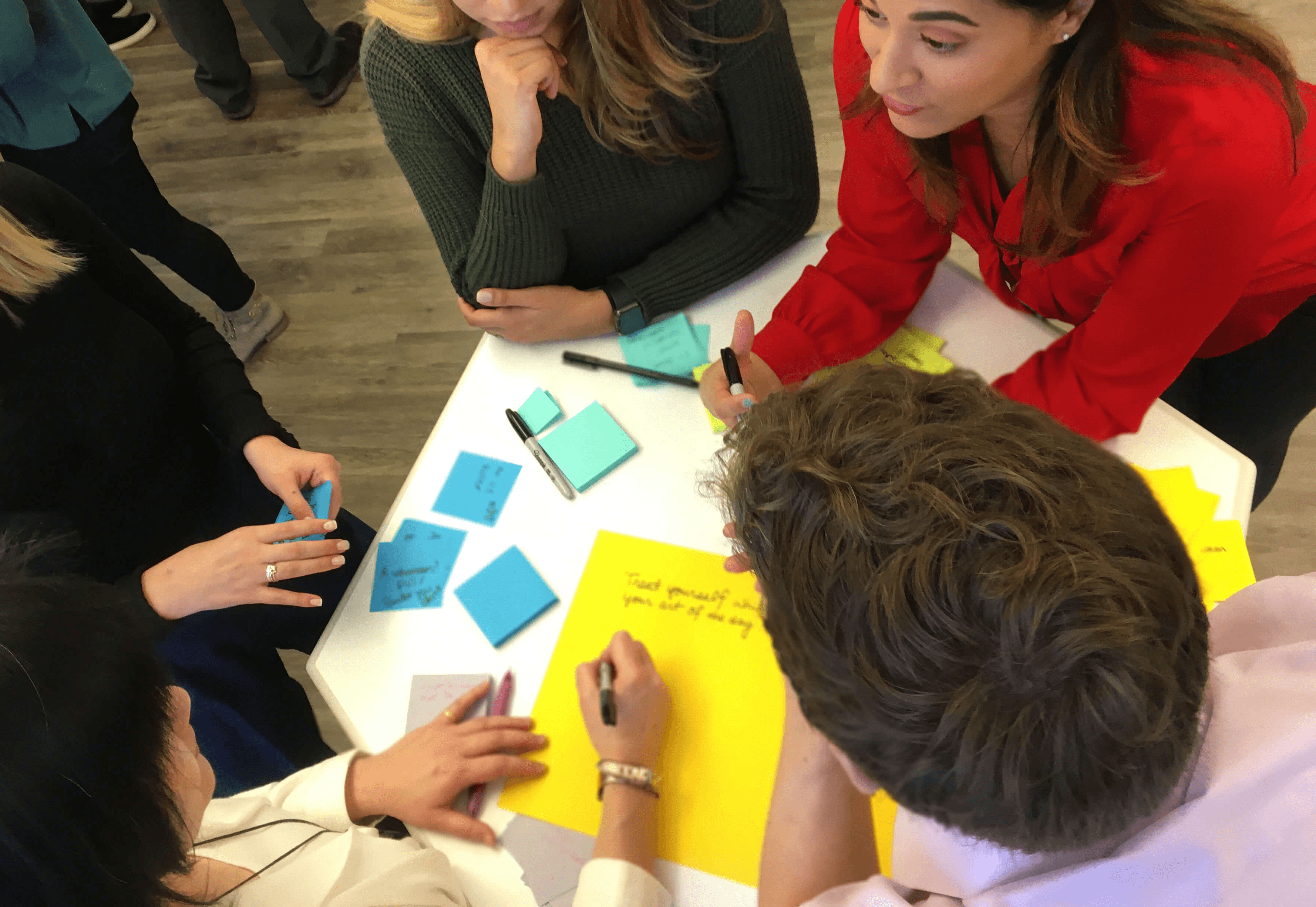 Group of young professionals collaborating around a table with colorful sticky notes during a brainstorming workshop