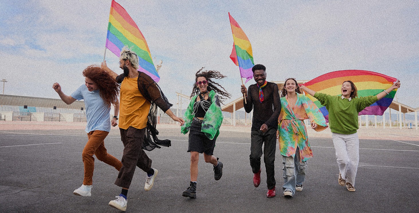 A group of people running on asphalt with pride flags.