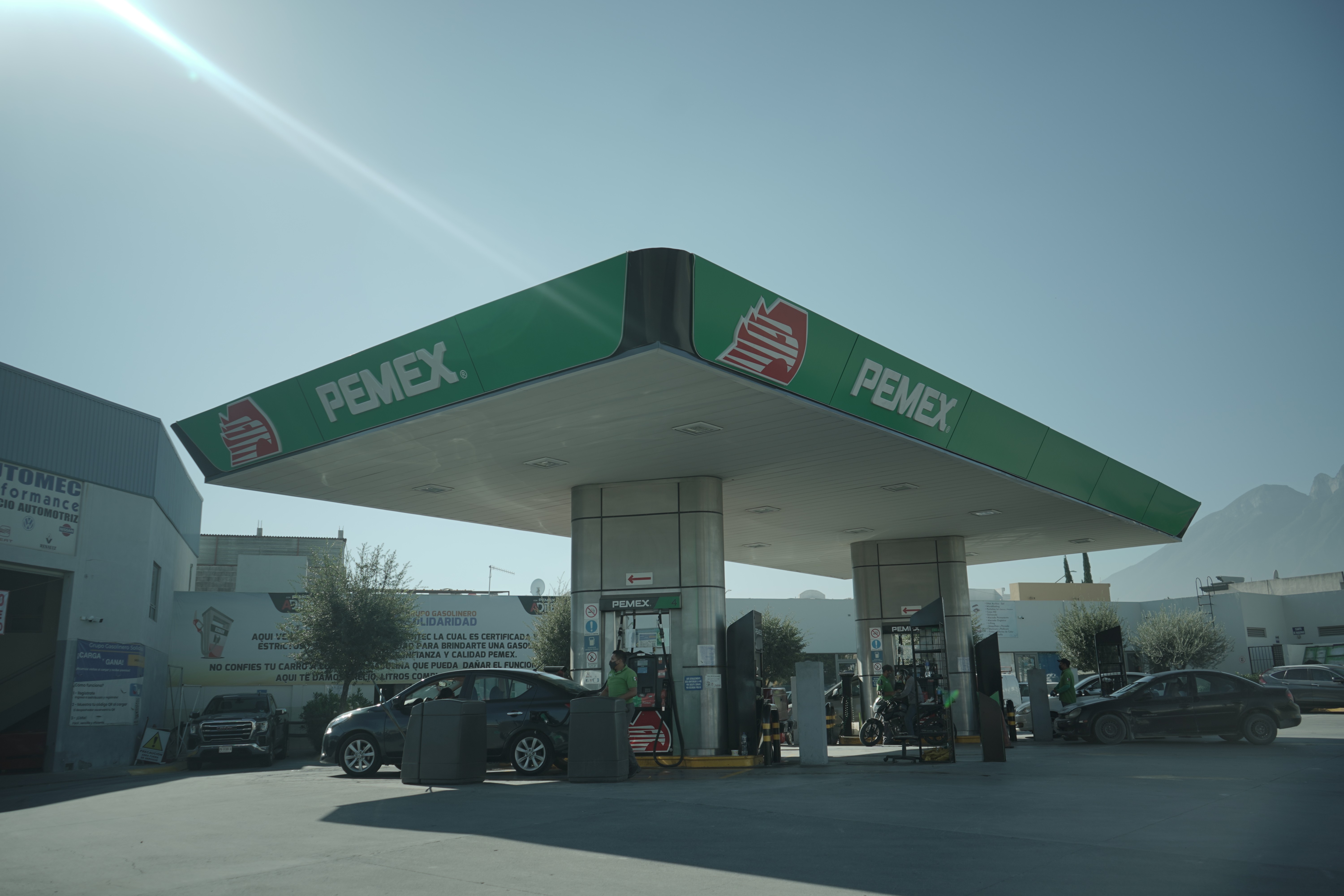 Modern indoor space with large glass doors, lush greenery, and a cozy seating area visible beyond.