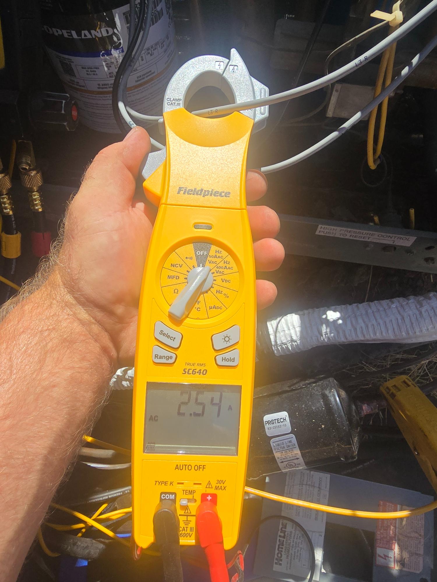 Technician using a Fieldpiece clamp meter to test HVAC electrical current.