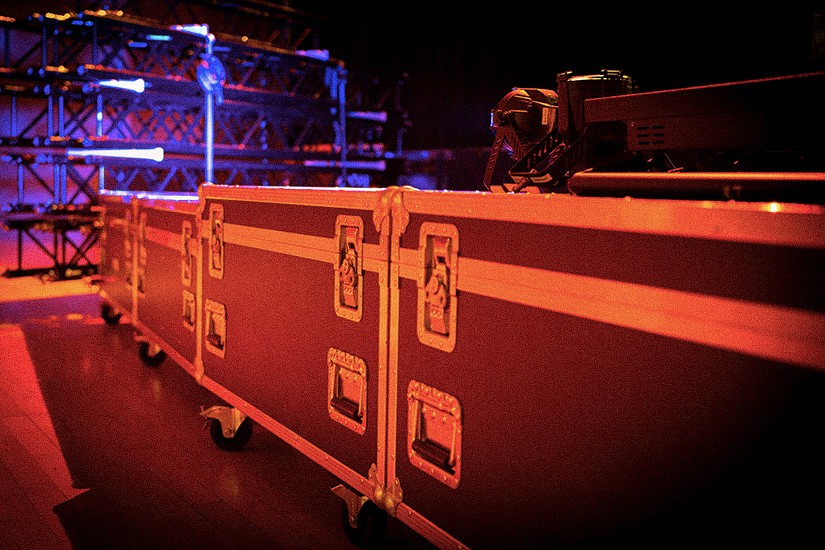 Un flightcase contenant le matériel son et lumières à côté d’une structure de scène de concert.