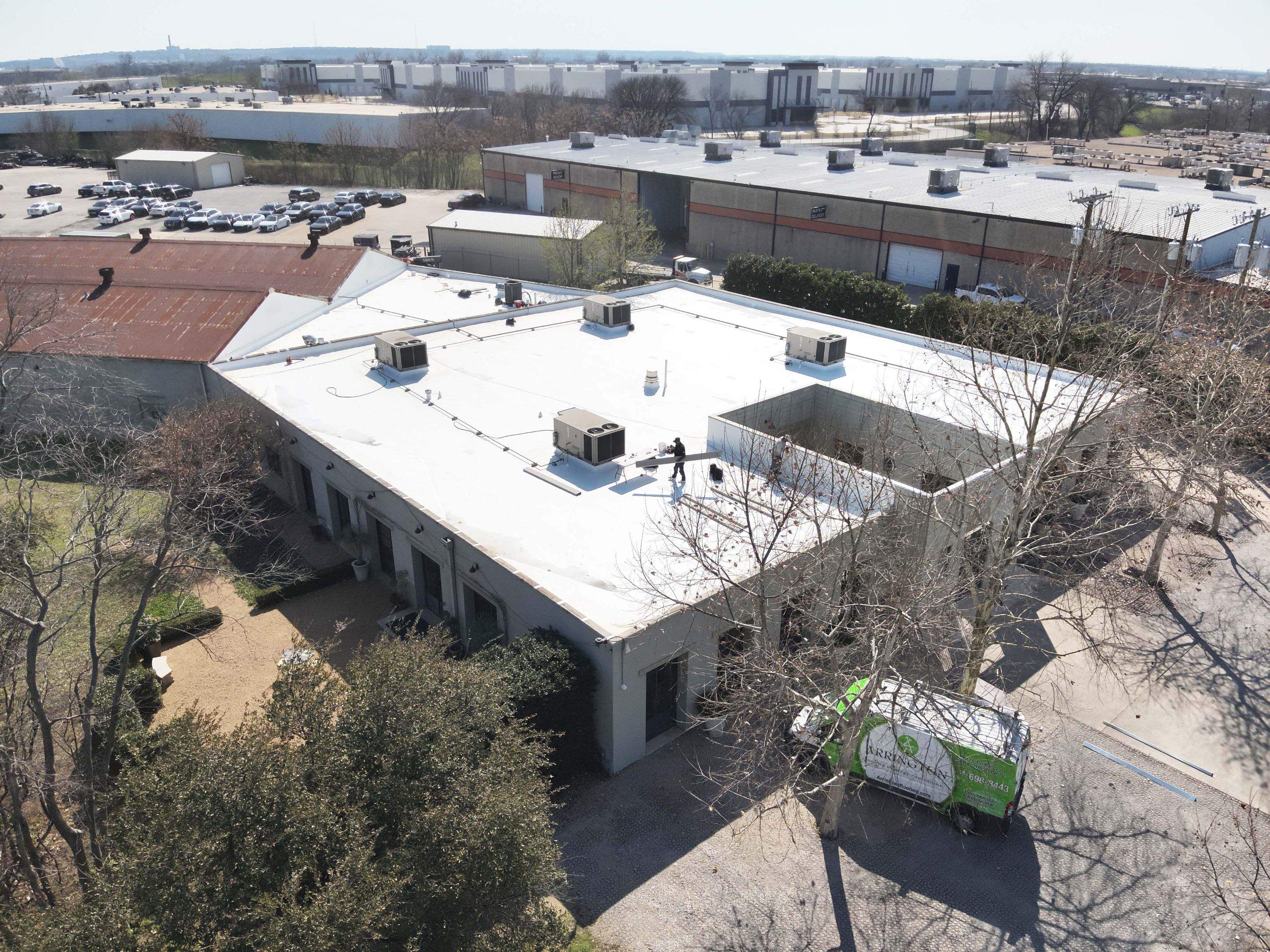 Aerial of the completed white TPO commercial roof in Dallas next to an adjacent metal-roofed structure