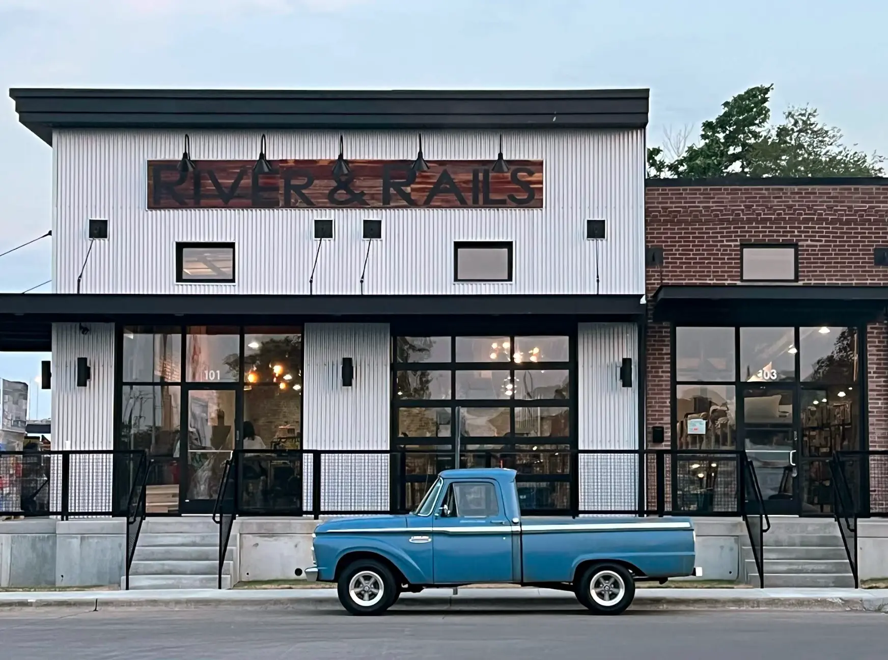 River & Rails retail storefront with modern industrial design and a vintage blue truck parked outside.