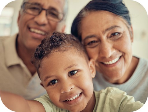 A warm, close-up selfie of a young, smiling boy with his two happy grandparents