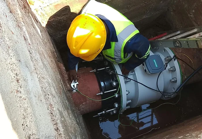 JOAT technician in a hard hat working on a meter installation inside an underground chamber