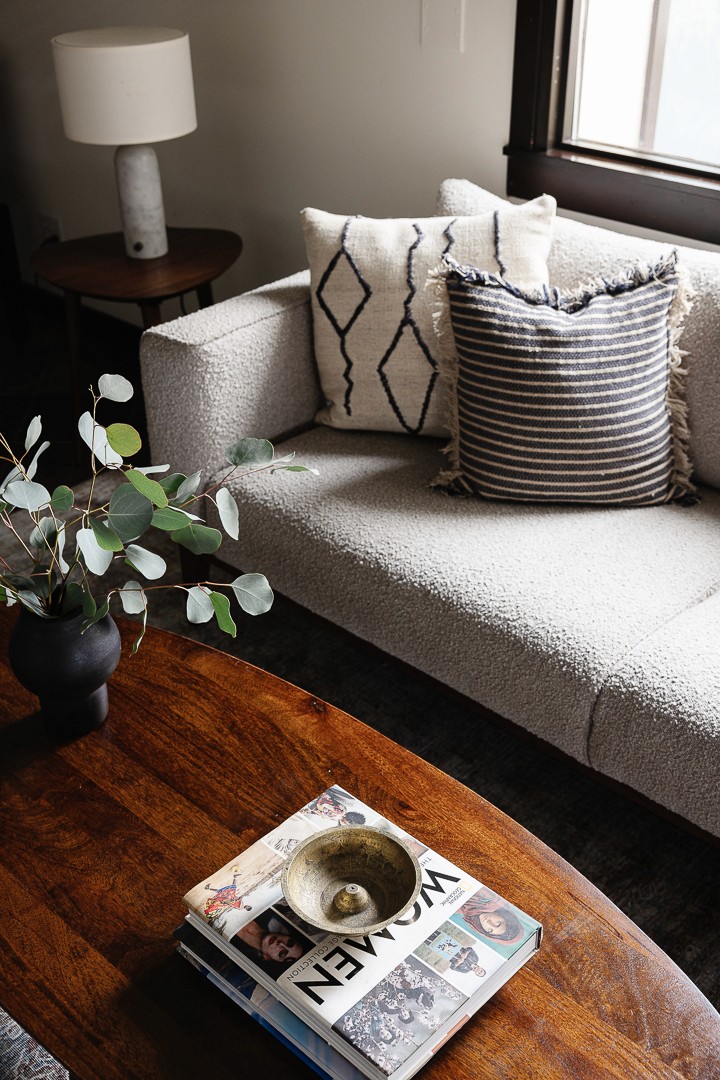 This outdoor oasis blends natural charm and refined luxury with a studded stone side table, linen accents, a sleek sun bed, large umbrella, and slate-inspired tiles, creating a harmonious sanctuary