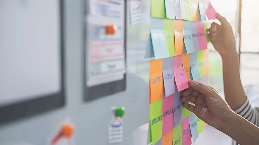 Person sticking post-it-notes onto a whiteboard.