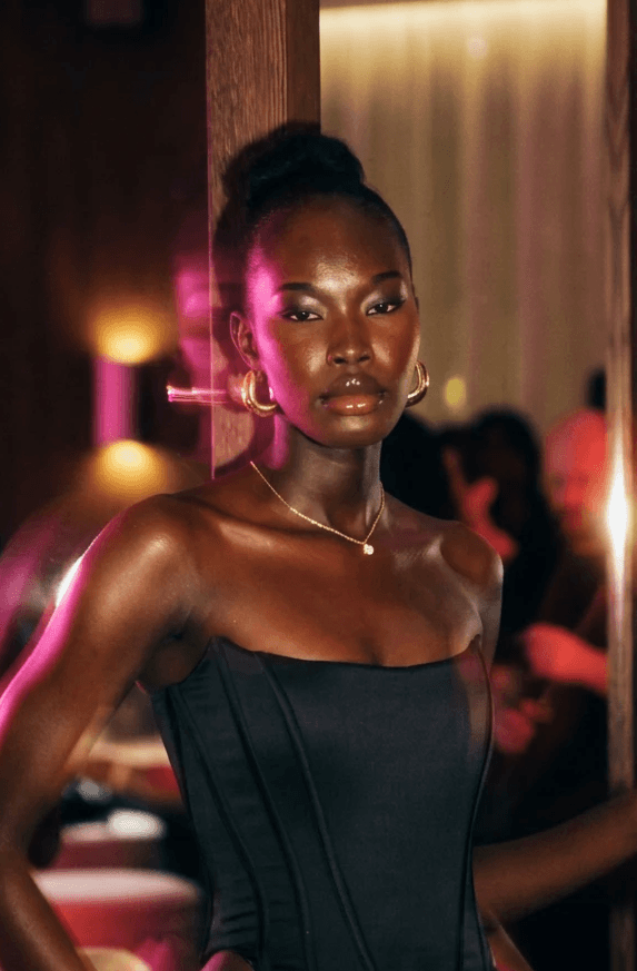 Woman in black outfit sitting on bar stool, leg extended