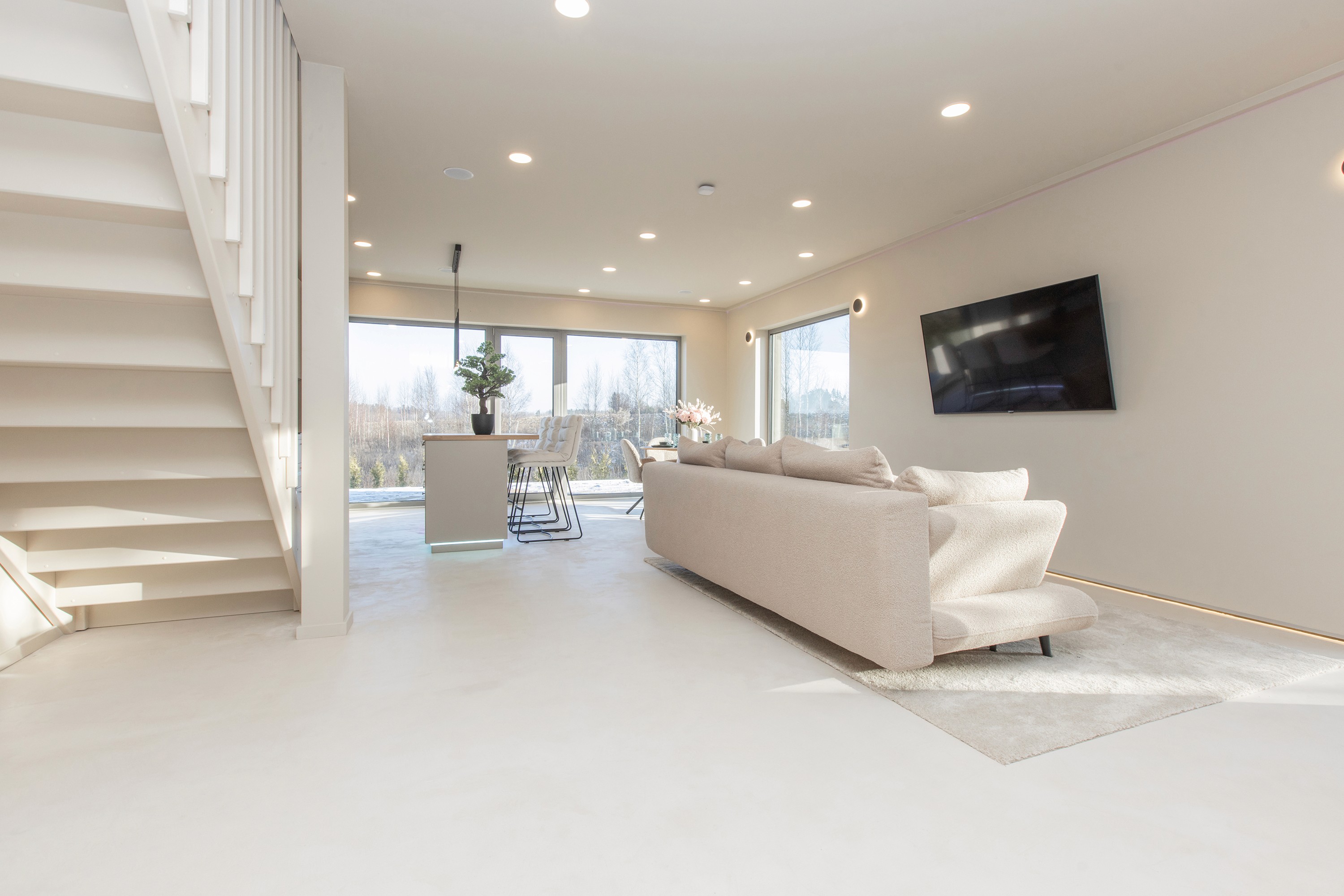 Bright living room interior with large windows and minimalistic design inside Priežavoti Village homes by Grande Build.