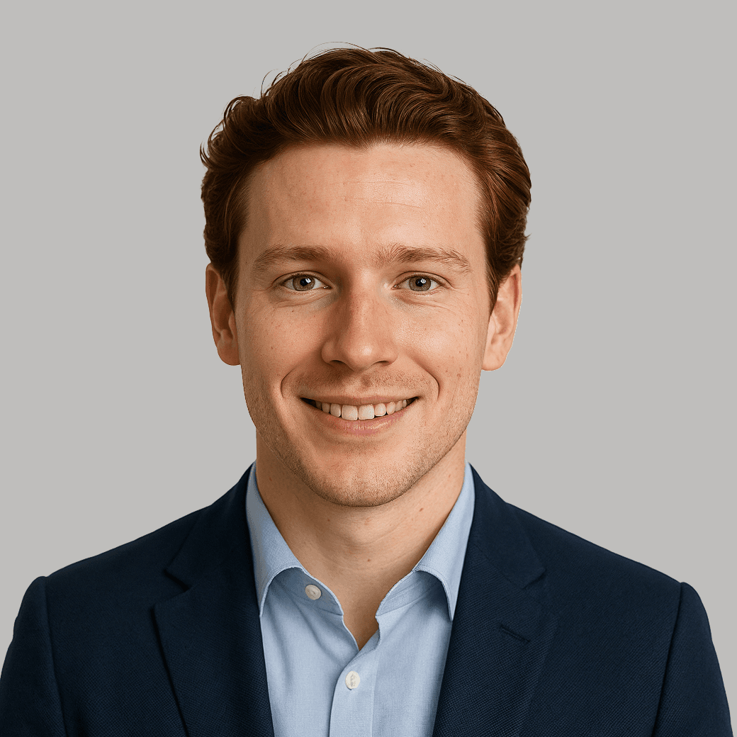 Portrait of a smiling young man with red hair, wearing a suit and light blue shirt.