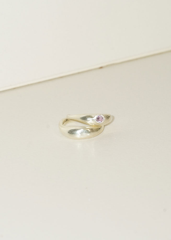 Silver ring with a pink gemstone on a beige background