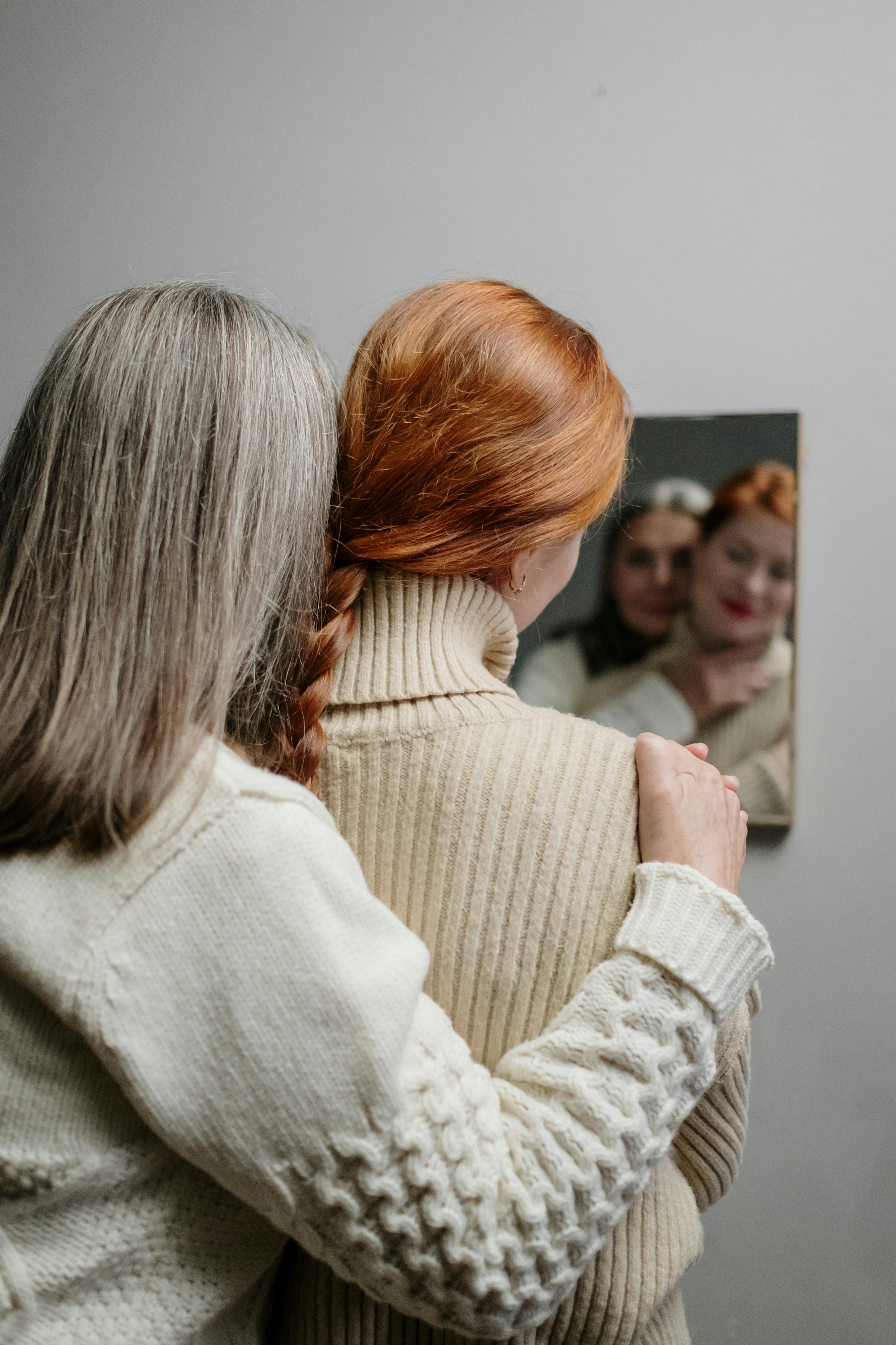 Conversion Truth for Families: An older mother with gray hair standing in front of a mirror with her red-haired teenage daughter.