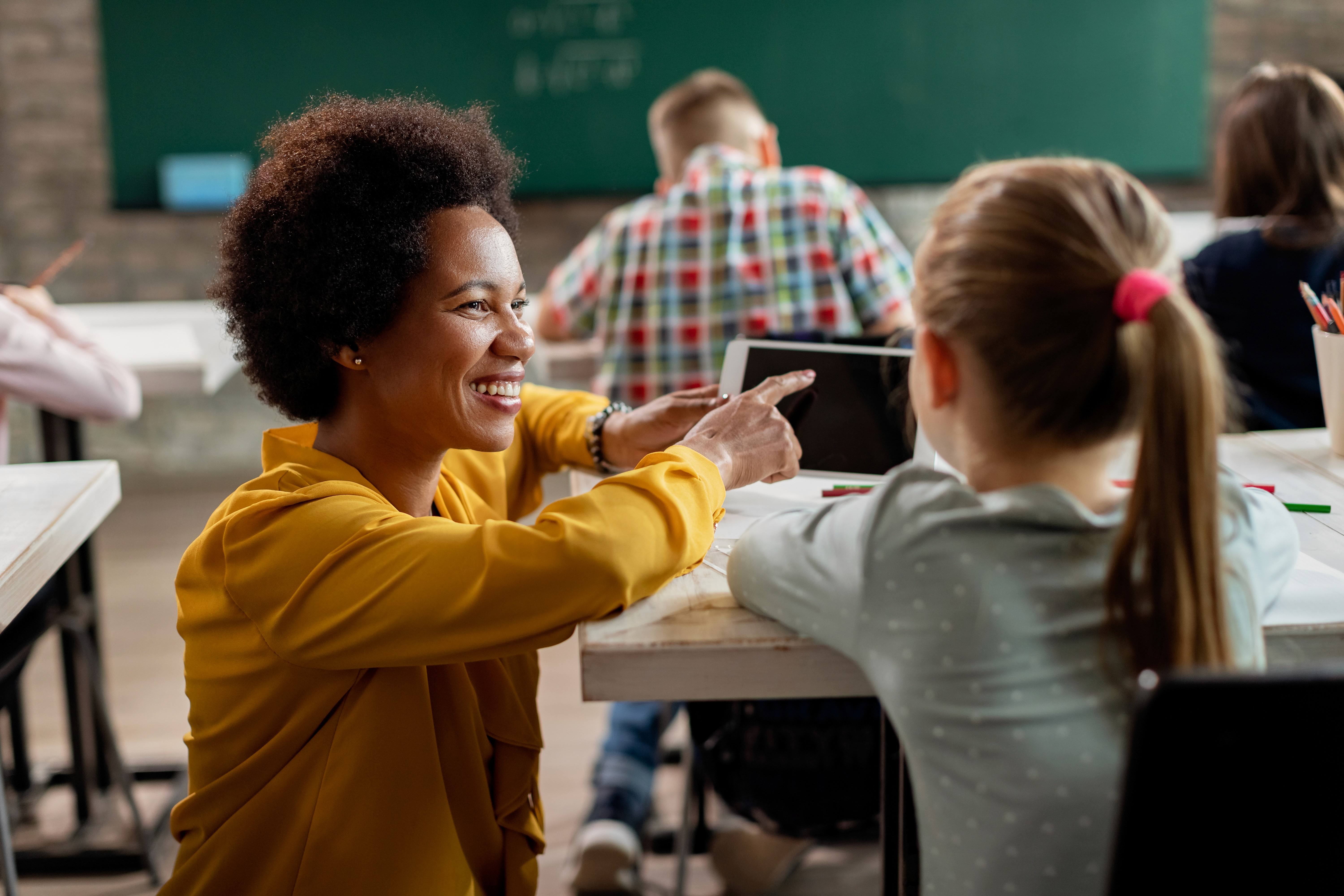 Teacher teaching a girl in class using a tablet