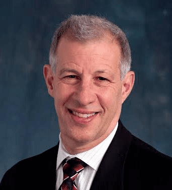 Larry Kessler MD in a black suit with a white shirt on a navy background