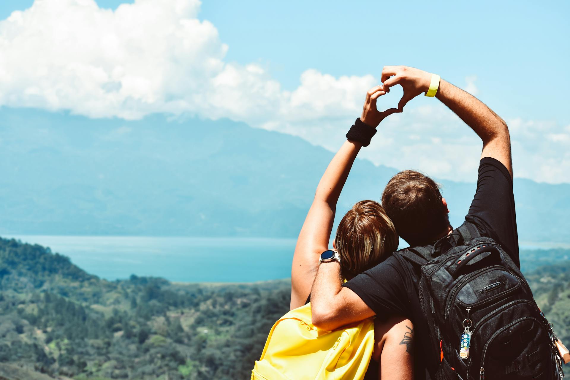 Couple hand sign in front of mountain