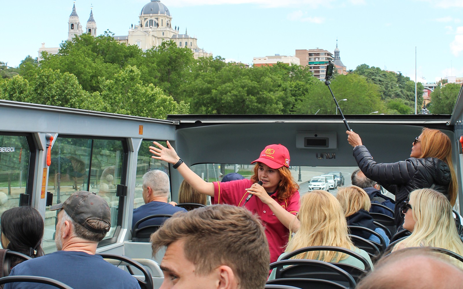 Guide som snakker med turister på toppdekket av Madrid Big Bus med Almudena-katedralen i sikte.