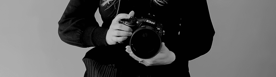 Abstract macro of a glass drop forming a black-and-white flower shape through light refraction on a soft gray background.