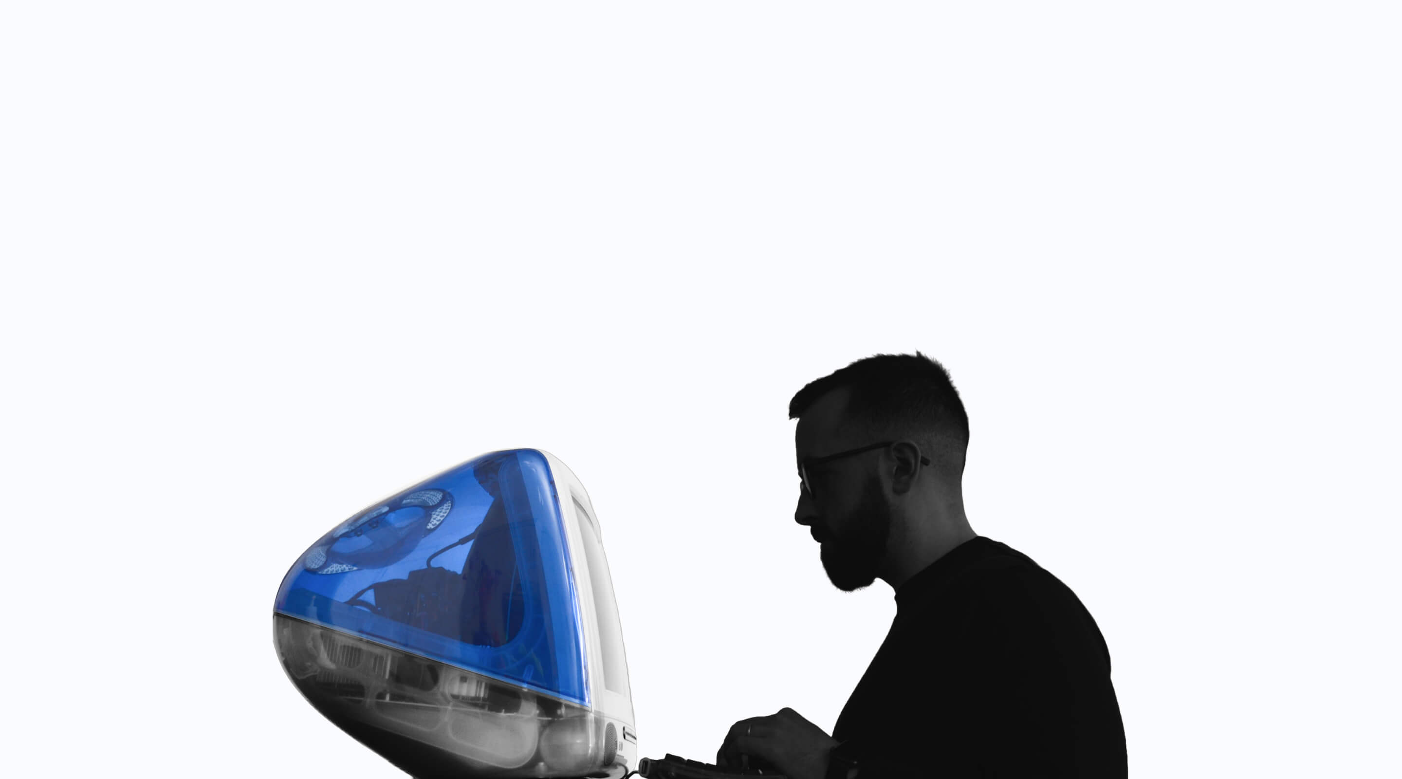 A photo of cormac, positioned from the side, facing a iMac G3 computer.