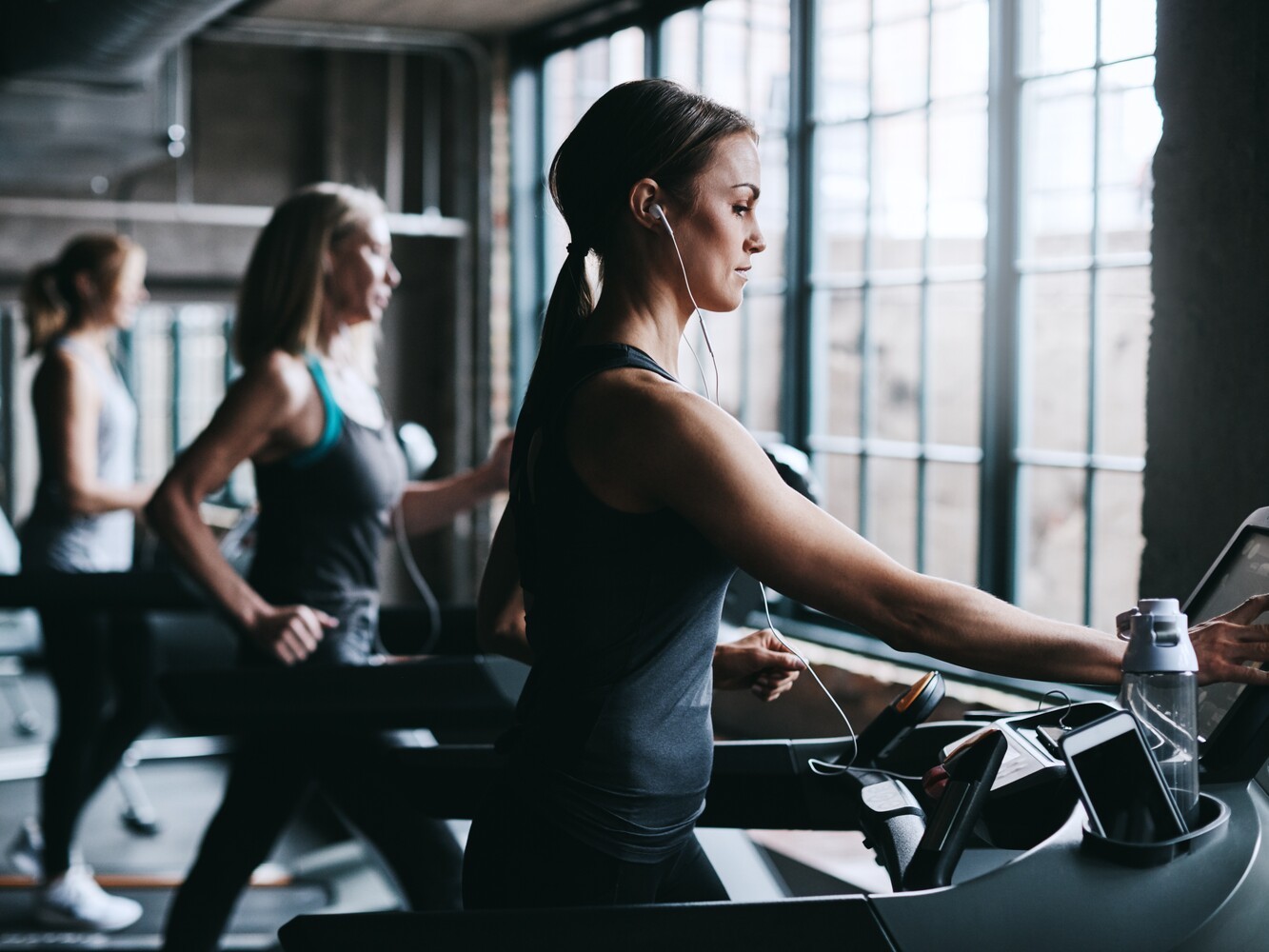 woman selecting settings as she prepares to do a 30-minute session of treadmill exercises for weight loss