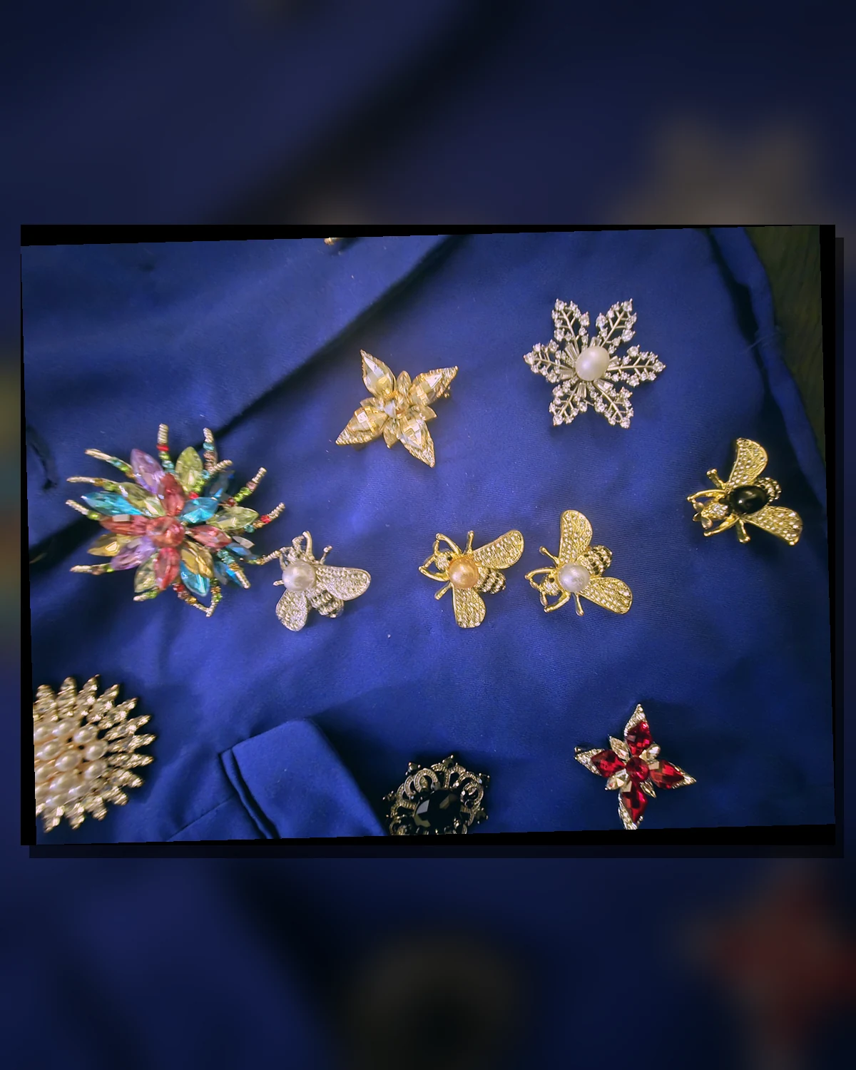 Macro field of the Wonder Suit's original insect and floral brooches under a teal-magenta filter.