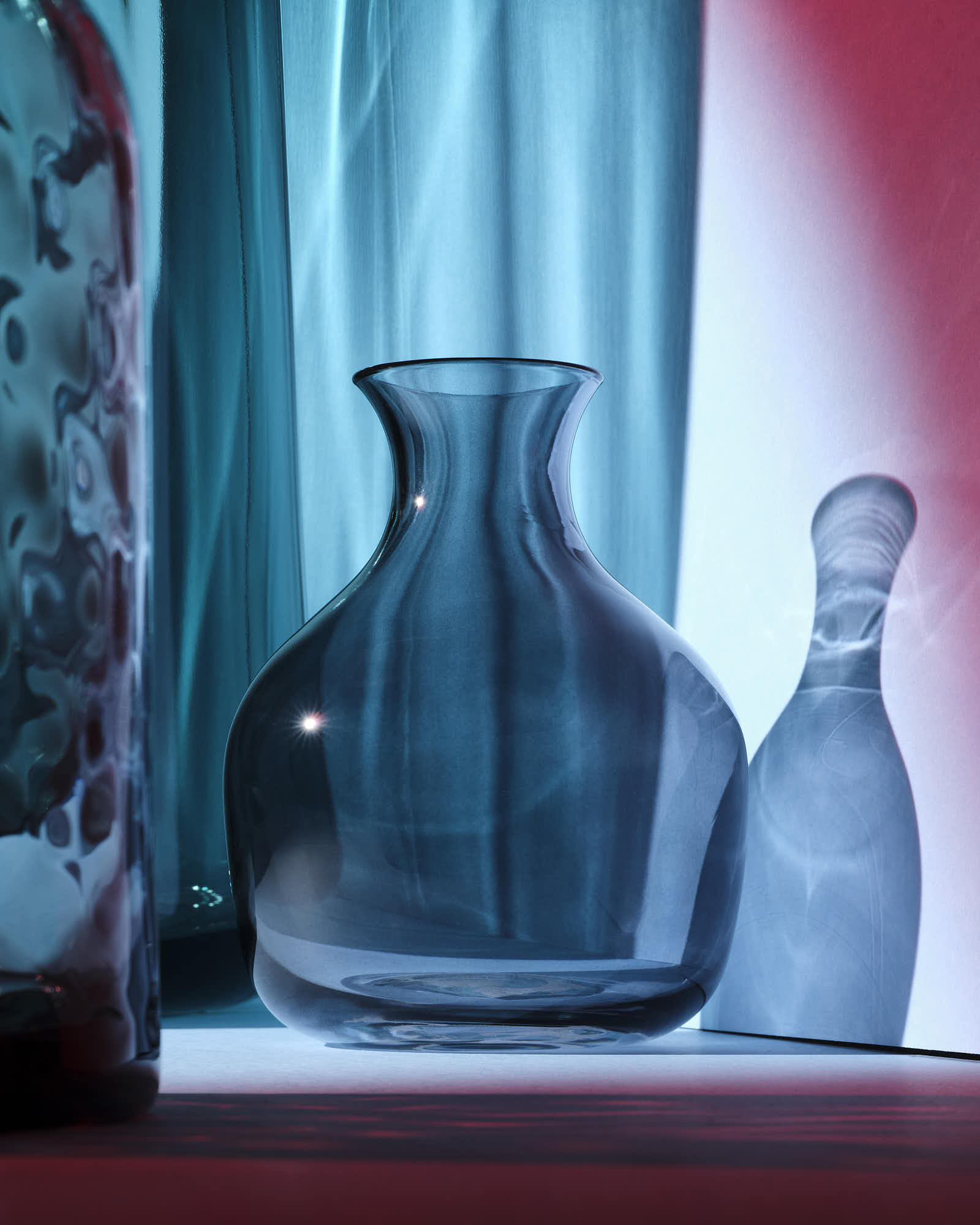 Elegant blue glass vase with dramatic lighting and shadows.