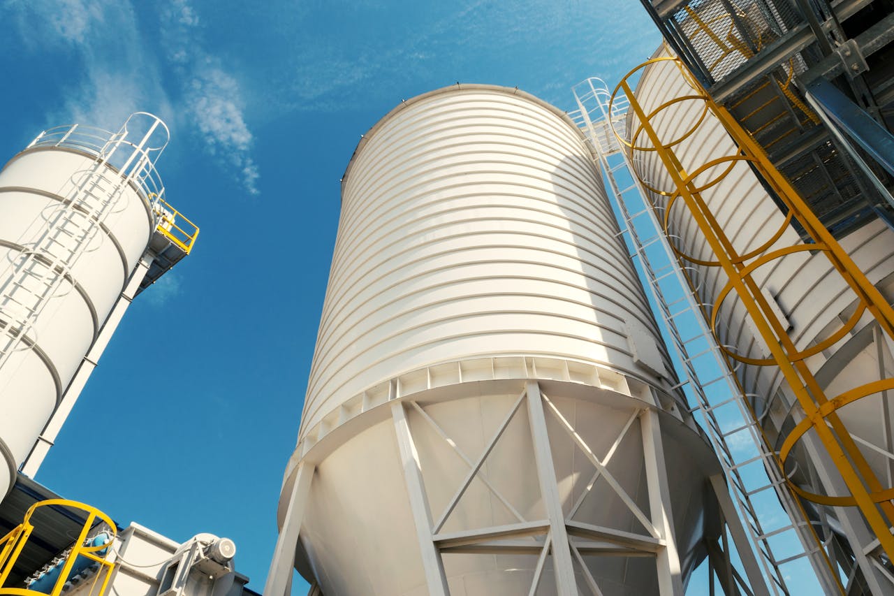 Wide-angle view of industrial silos with clear blue sky, captured during daytime, showcasing modern industry.