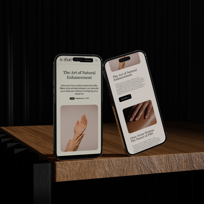 Two smartphones displaying the Shae Medical Aesthetics blog on a wooden surface, with articles titled 'The Art of Natural Enhancement' and 'Glow From Within: The Power of PRP,' featuring images of hands and skin treatments.