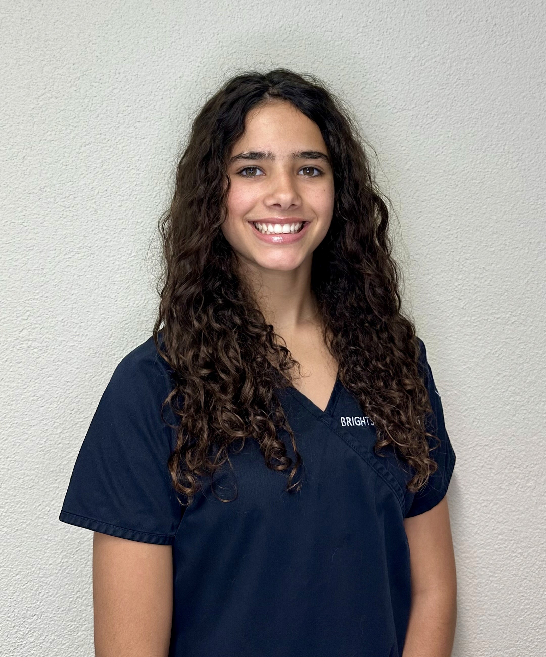 Dentalassistentin Saphira Fernandez mit lockigen Haaren beim Vorbereiten einer Behandlung.