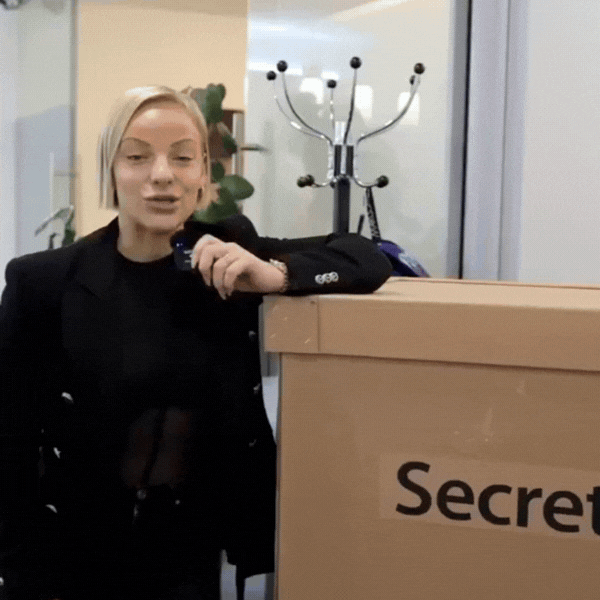 A stylish individual in a black shirt and silver pants stands against a blurred background, creating a dynamic and modern aesthetic.