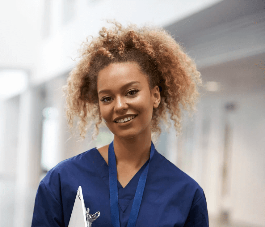 A smiling doctor with glasses and stethoscope stands arms crossed.