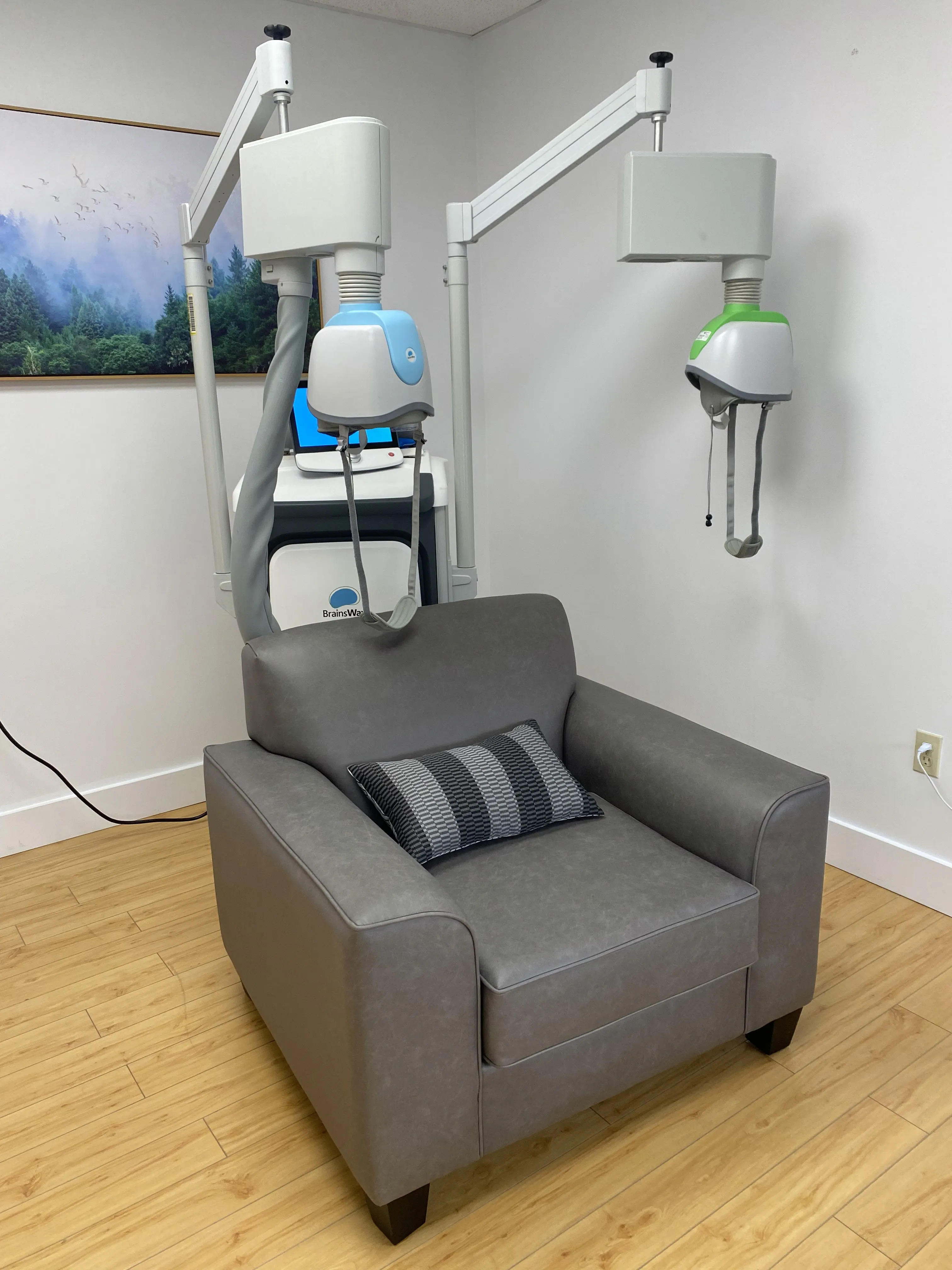 Deep TMS treatment devices with coils mounted on either side of a gray leather recliner chair