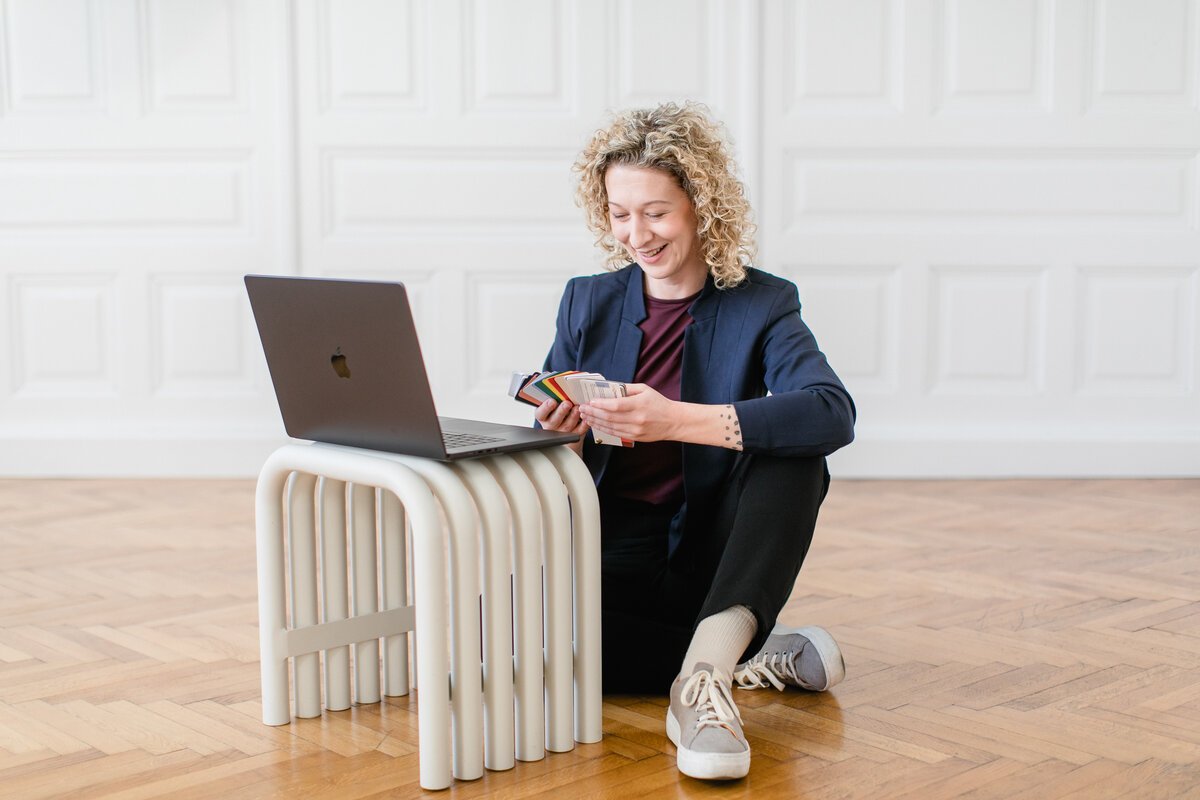 UI/UX-Designerin Sandra Kitting arbeitet am Laptop mit Farbmustern für ein Designprojekt