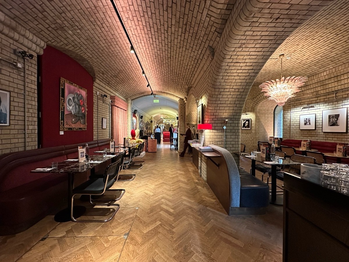 Larry's at the National Portrait Gallery. Path straight. Hald booth on left. More seating right. Vaulting cielings over head.