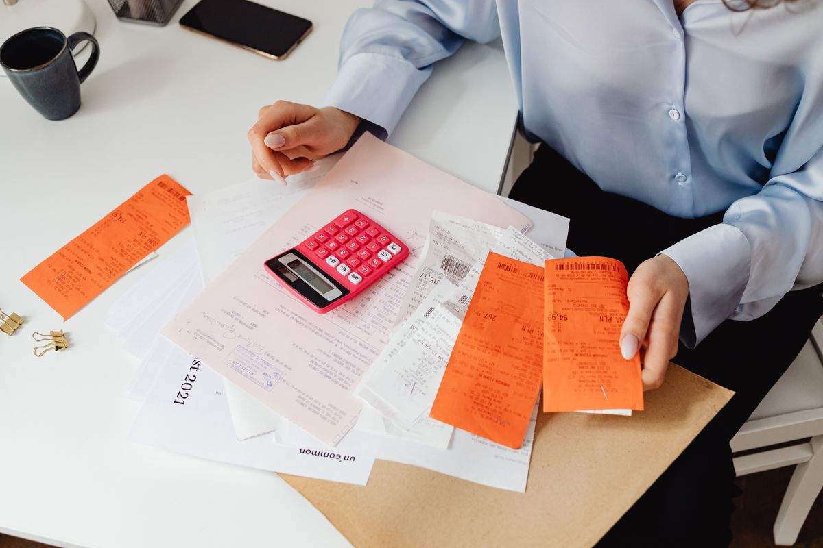 A person reviewing receipts with a calculator while budgeting monthly expenses