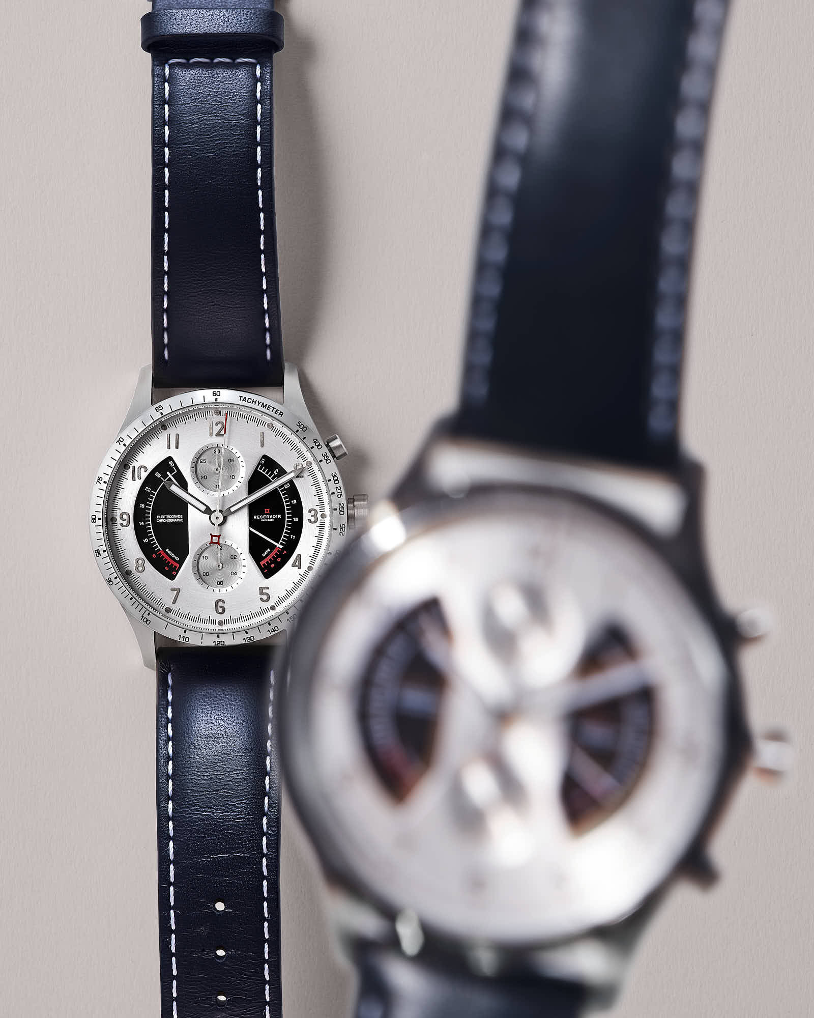 Luxury men's wristwatch with tachymeter and navy leather strap.