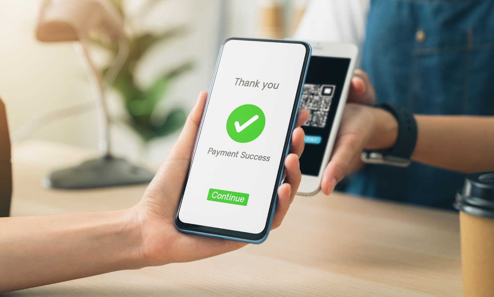Person holding a phone that says “thank you payment success” next to a checkmark. 