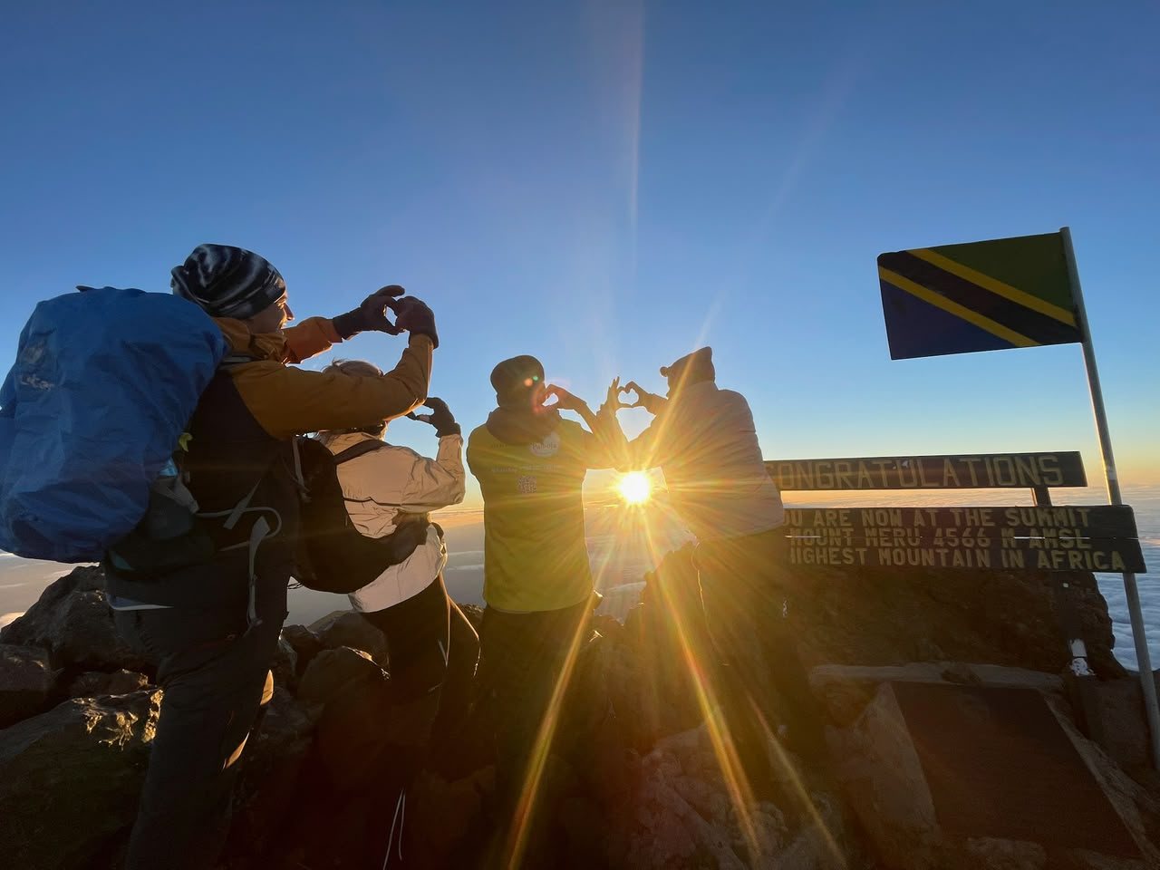 Travellers celebrating at the summit of Mount Meru at sunrise.