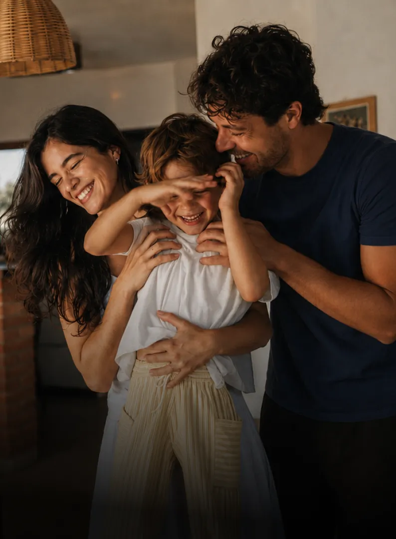 Família sorrindo na entrada de uma casa.