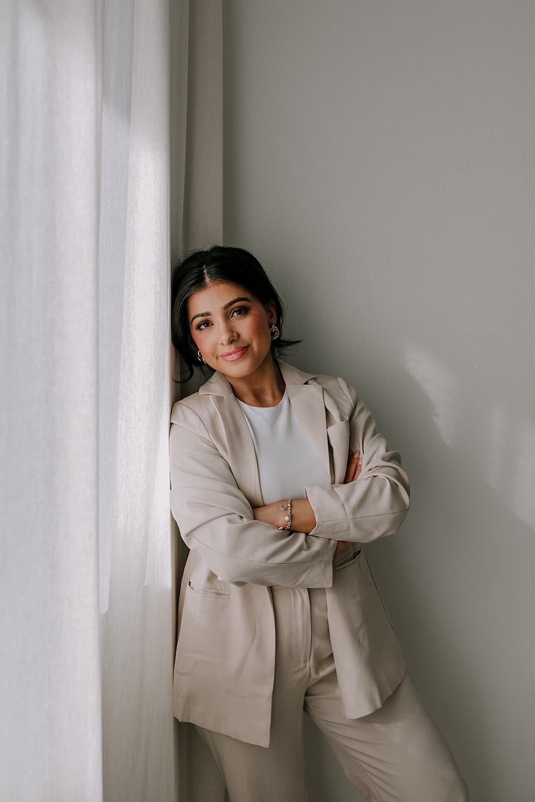 Haley Gould stands confidently by a window, natural light enhancing the professional atmosphere of Revelator Studio in Shreveport.