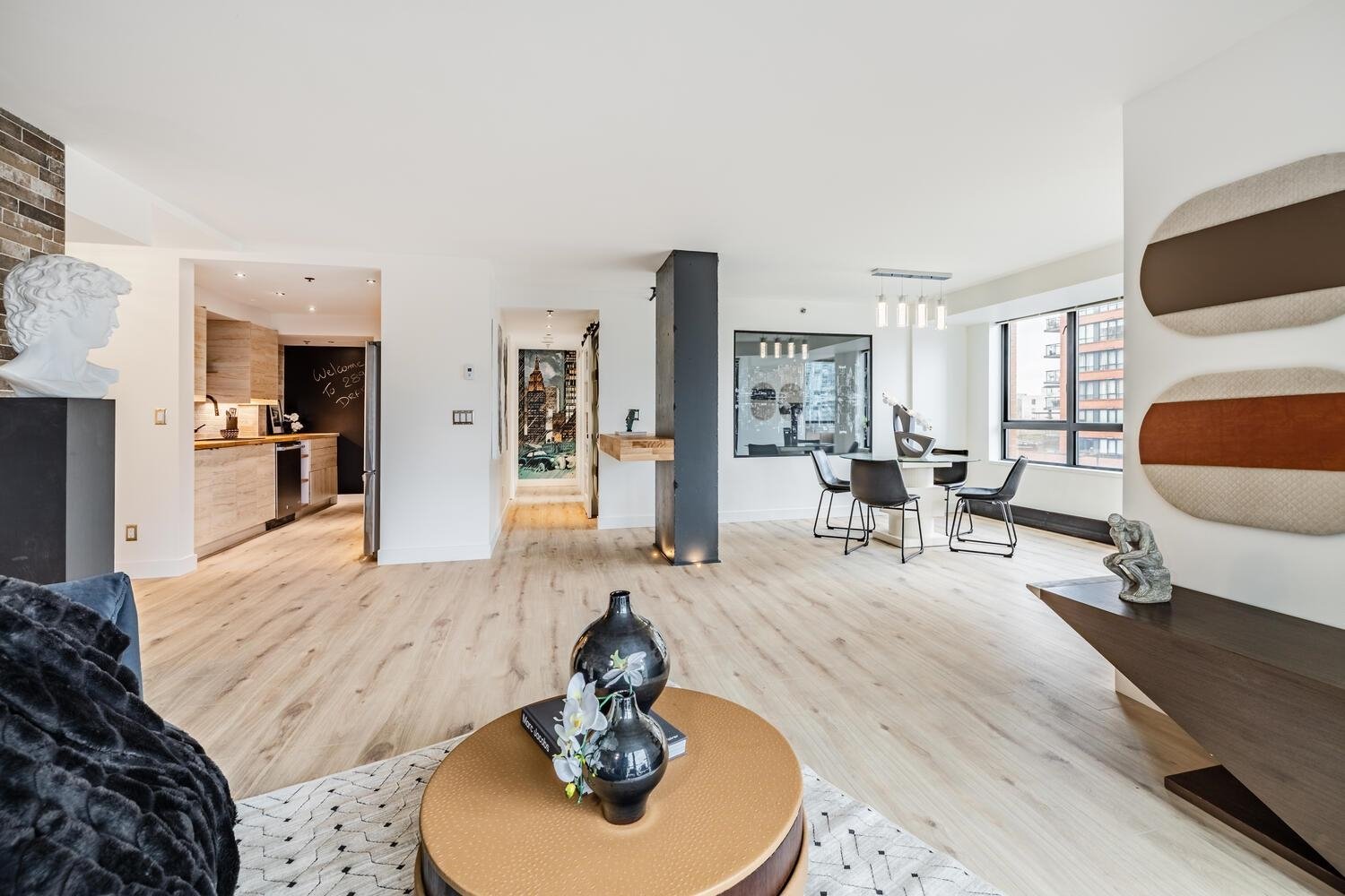 Spacious living area featuring modern decor, a round coffee table, and large windows allowing natural light.